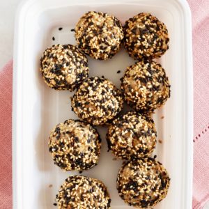 Sesame walnut balls inside a white container, over a pink napkin.