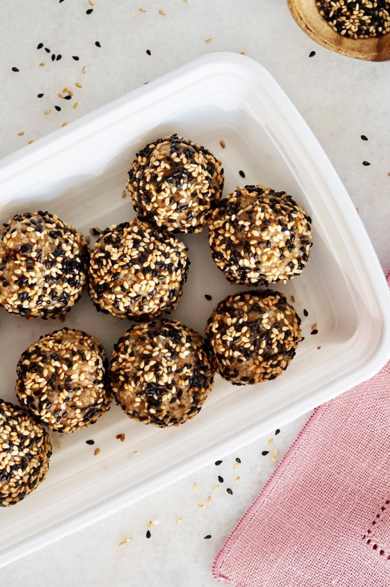 Sesame walnut balls inside a white container, over a pink napkin.